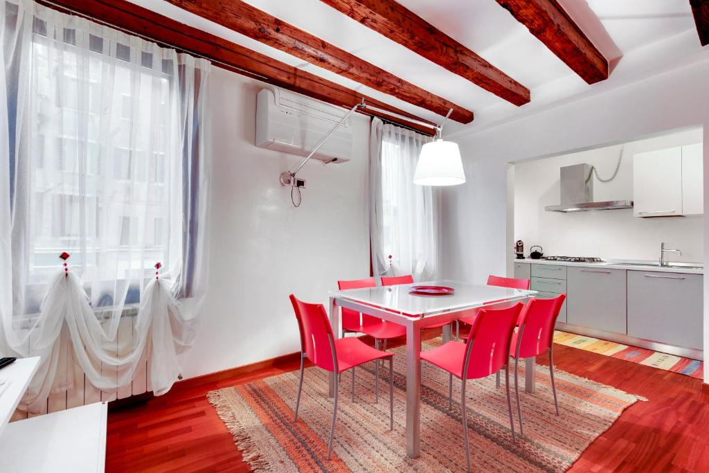 cocina y comedor con mesa blanca y sillas rojas en Apartment Biennale, en Venecia