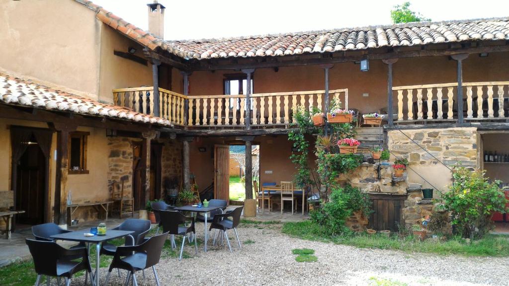 eine Terrasse mit Tischen und Stühlen vor einem Gebäude in der Unterkunft Casa Rural Las Águedas in Murias de Rechivaldo