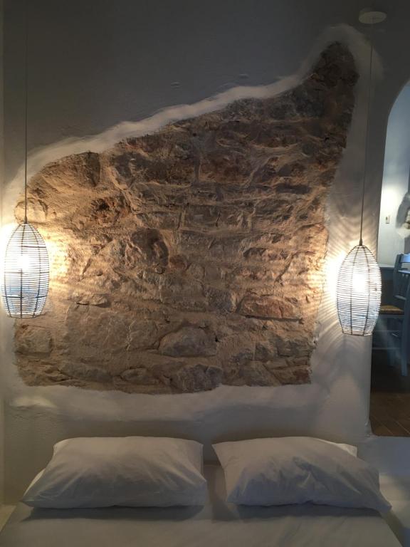 a bedroom with two pillows and a stone wall at Astrofegia guest house in Donoussa