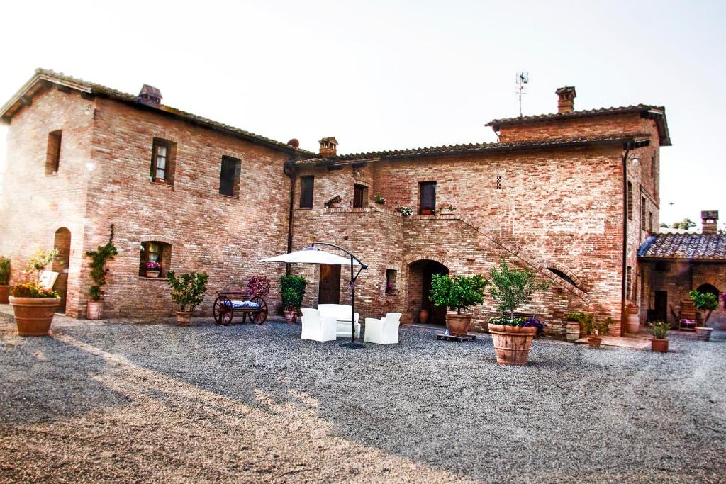 ein großes Backsteingebäude mit Stühlen und einem Regenschirm in der Unterkunft Agriturismo San Pierino in Monteroni dʼArbia