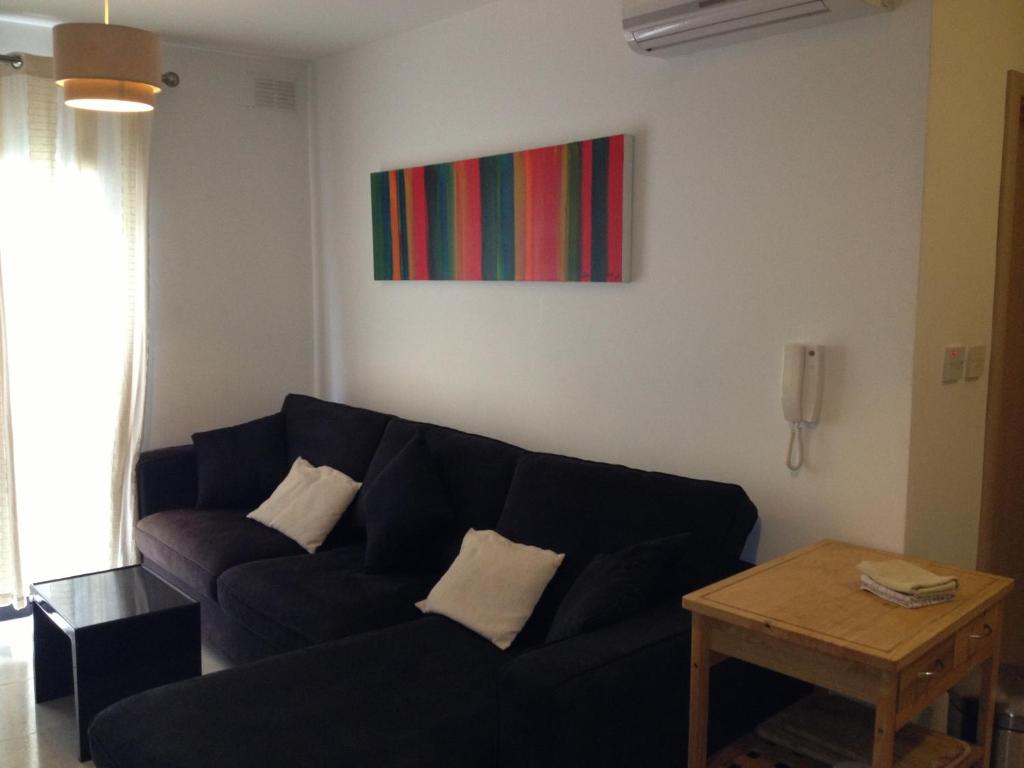 a living room with a black couch and a table at Paceville Avenue Apartment in St Julian's
