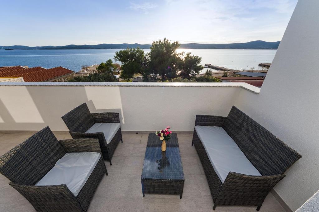 a balcony with three chairs and a table with flowers at Apartment Paulo&Lorenco in Sveti Filip i Jakov