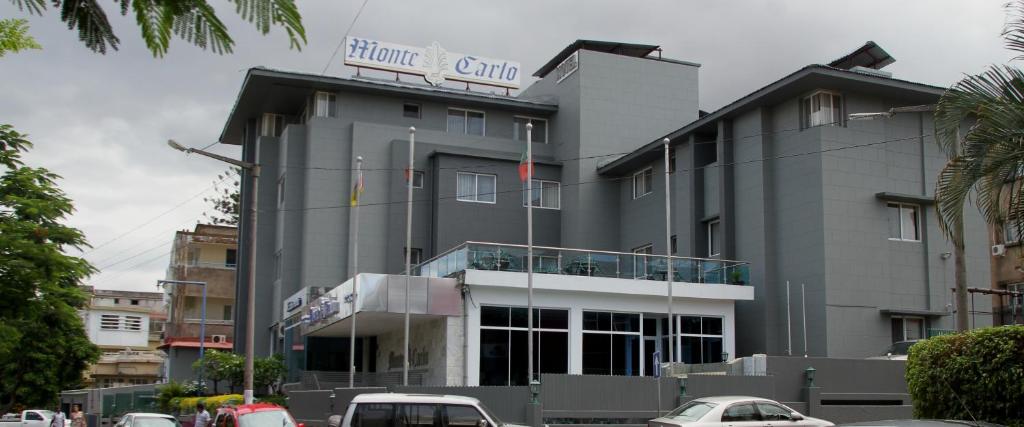 un gran edificio gris con coches estacionados frente a él en Hotel Monte Carlo, en Maputo