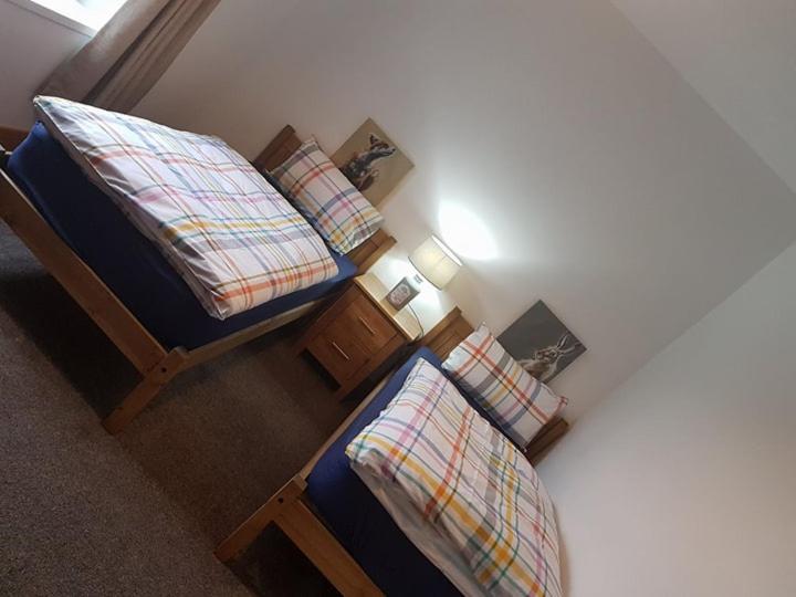 1 dormitorio con 2 camas individuales y mesita de noche en Yvi's 2-3 Bedroom Town Apartment, en Inverurie