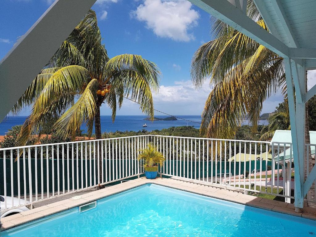 a swimming pool on a balcony with a view of the ocean at Les Petites Fleurs de Poirier in Bouillante