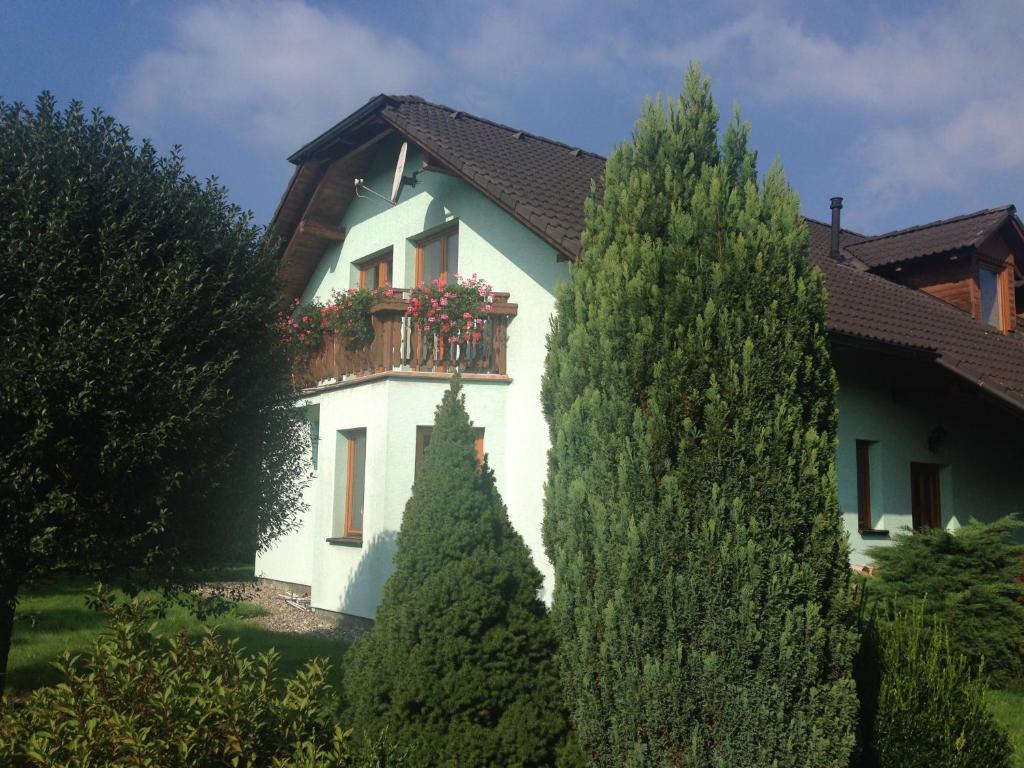 a white house with a balcony and two trees at Penzion Svatava in Ostrava