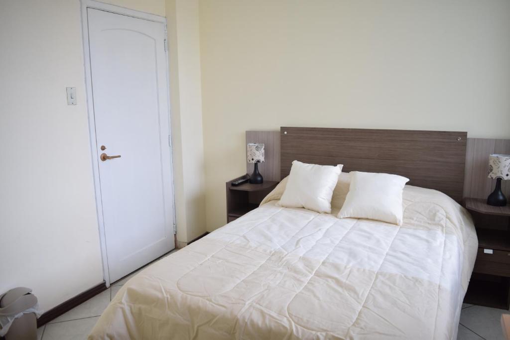 1 dormitorio con 1 cama blanca grande y 2 almohadas en Alojamiento Castelnouvo, Entre Ríos, Guayaquil, Ecuador, en Guayaquil