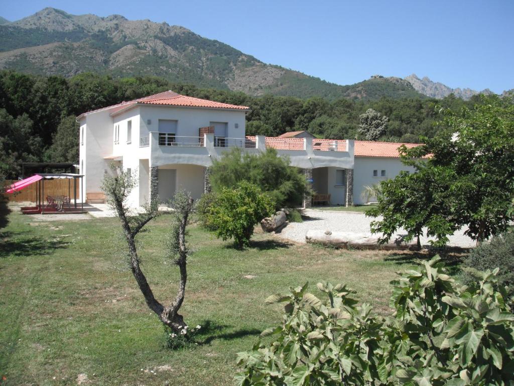 une maison blanche avec des arbres et des montagnes en arrière-plan dans l'établissement L'Attrachju, à Corte