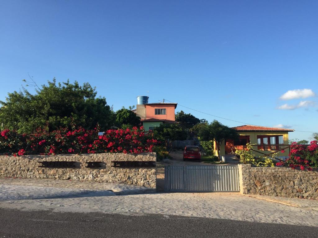 een huis met een stenen hek en bloemen bij Sobre as Pedras Chalés in Monte das Gameleiras