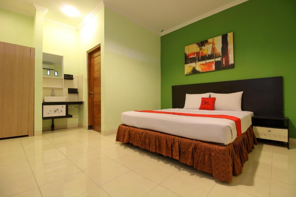 a bedroom with a large bed with a green wall at RedDoorz Plus @ Taman Siswa 2 in Yogyakarta