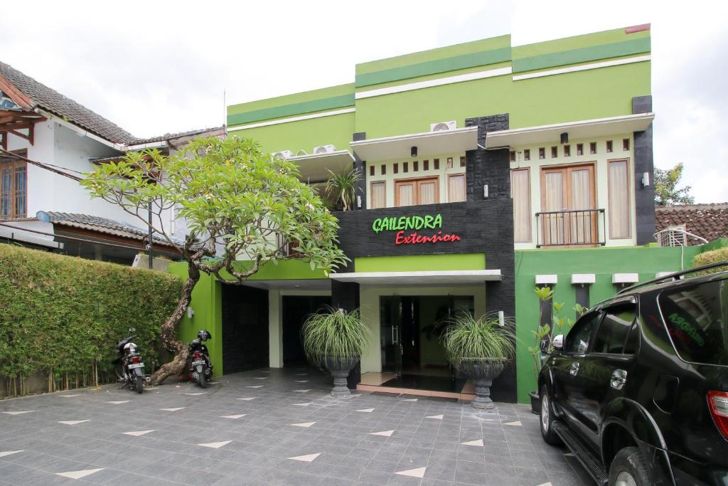 a green building with a car parked in front of it at RedDoorz Plus @ Taman Siswa 2 in Yogyakarta