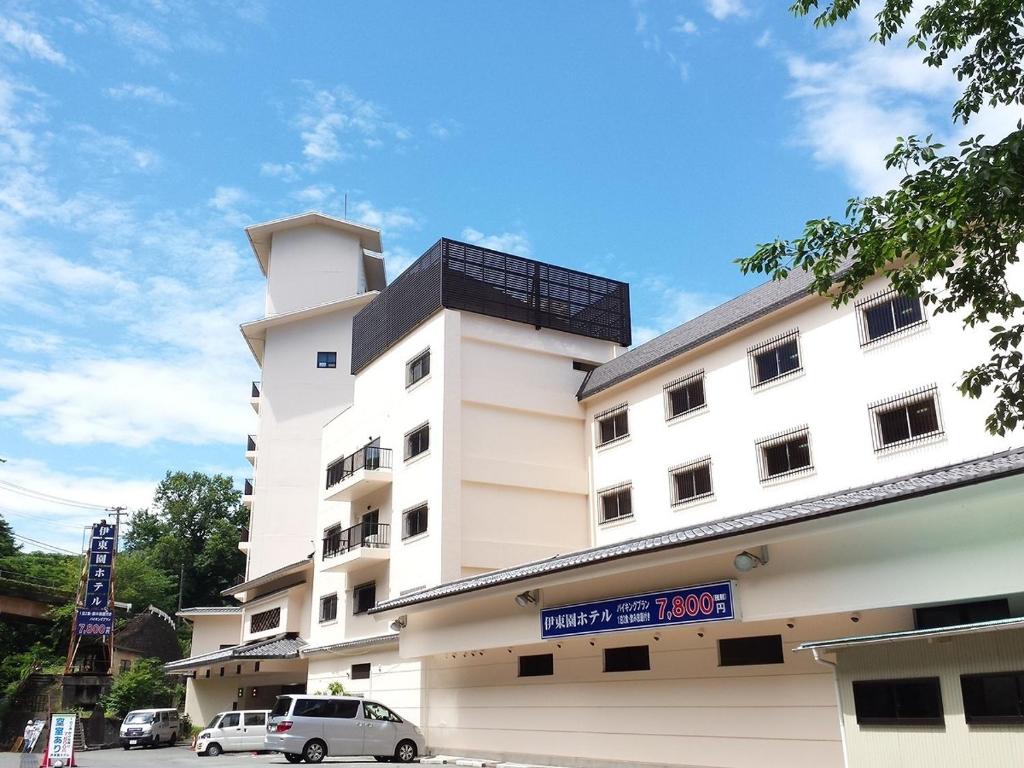 a white building with cars parked in front of it at Itoen Hotel Atagawa in Higashiizu