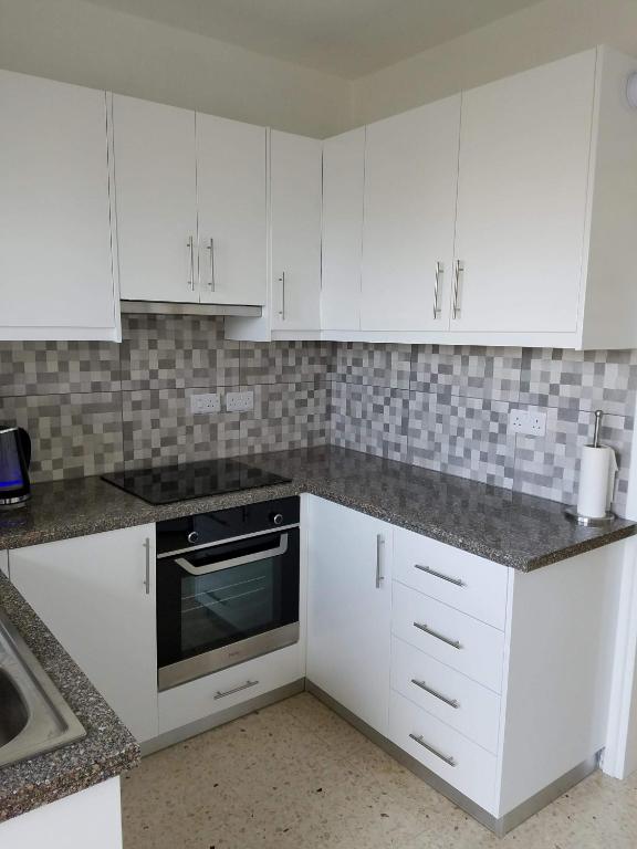 a white kitchen with white cabinets and a sink at Kings Avenue - Natalia's Apt in Paphos