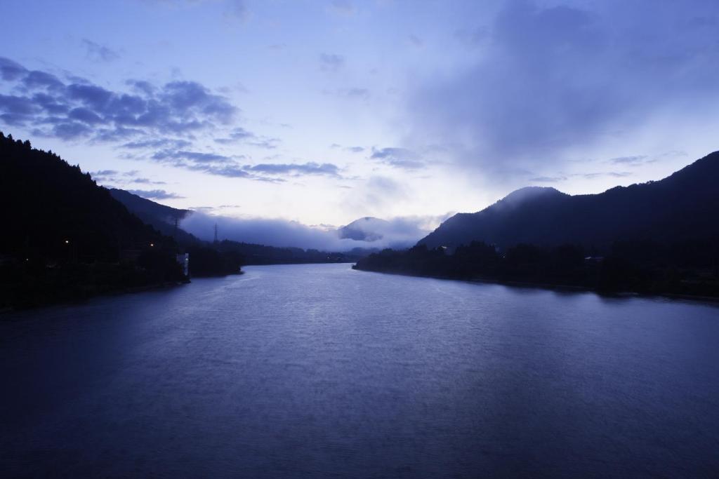 a view of a river with mountains in the background at Satorikan in Gosen