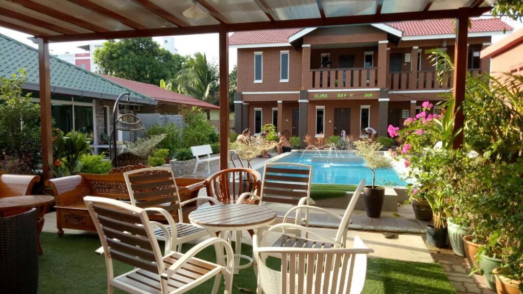 um pátio com cadeiras, uma mesa e uma piscina em D lima beach inn em Pantai Cenang