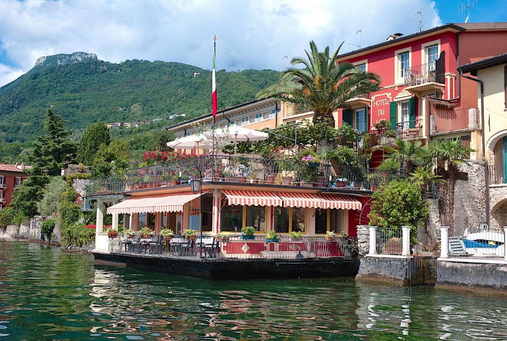 a boat on a river in front of a building at Hotel Du Lac in Gargnano