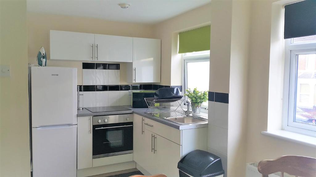 a kitchen with white cabinets and a sink and a refrigerator at Swindon Old Town Duplex - EnterCloud9SA in Swindon