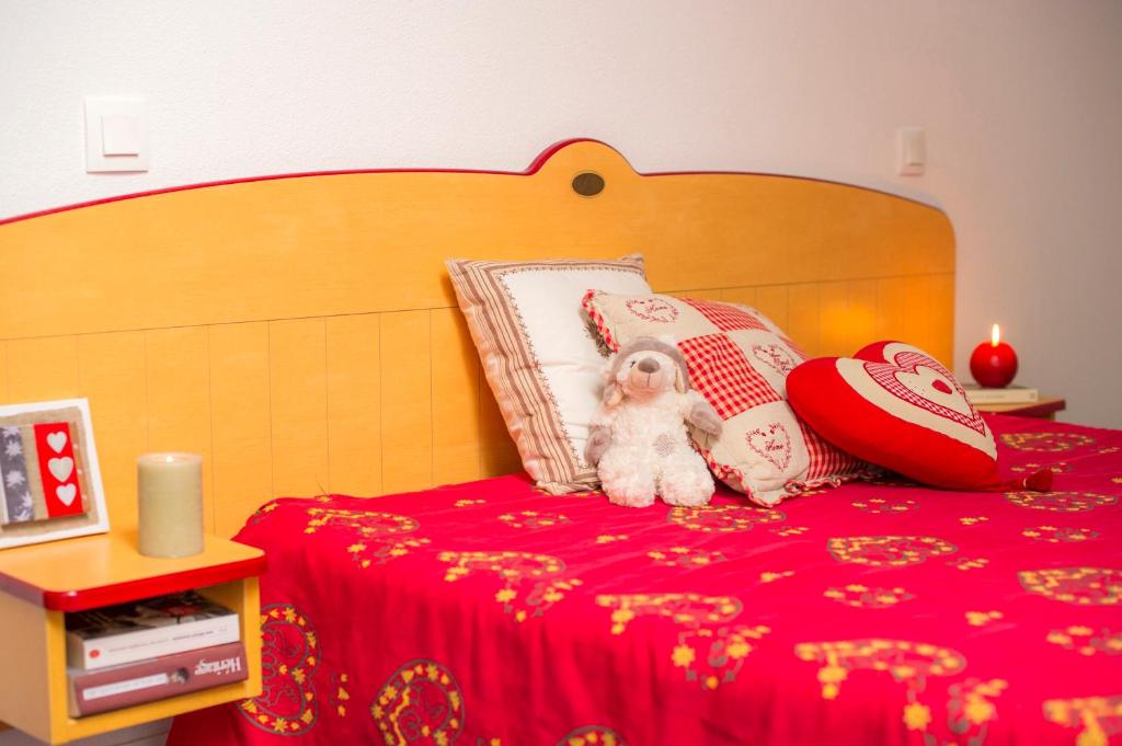 a teddy bear sitting on a bed with pillows at Résidence Goélia Les 4 Vallées in Saint-François-Longchamp