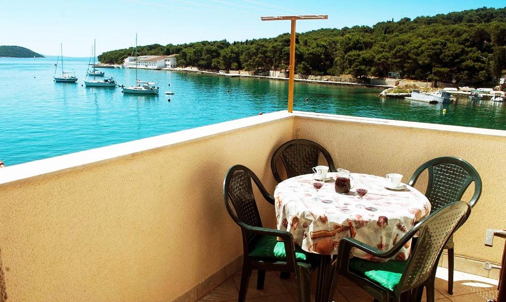 a table on a balcony with a view of the water at Apartment Bogadi in Prvić Luka