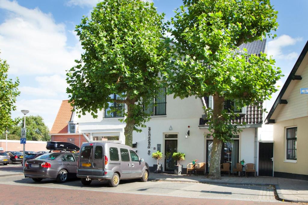 two cars parked in a parking lot in front of a building at Boutique Hotel De Raetskamer in Noordwijkerhout
