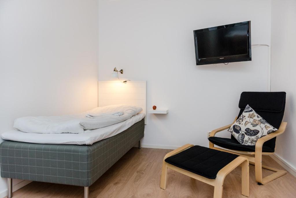 een kleine slaapkamer met een bed en een stoel bij Strömbäcks Vandrarhem in Umeå