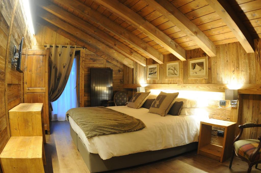 ein Schlafzimmer mit einem großen Bett in einem Zimmer mit Holzwänden in der Unterkunft L'Abri des Amis in Courmayeur