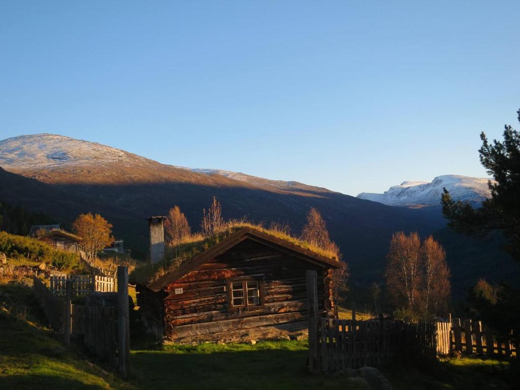 Cabaña de madera con valla y montañas al fondo en Strind Gard, Visdalssetra, en Boverdalen