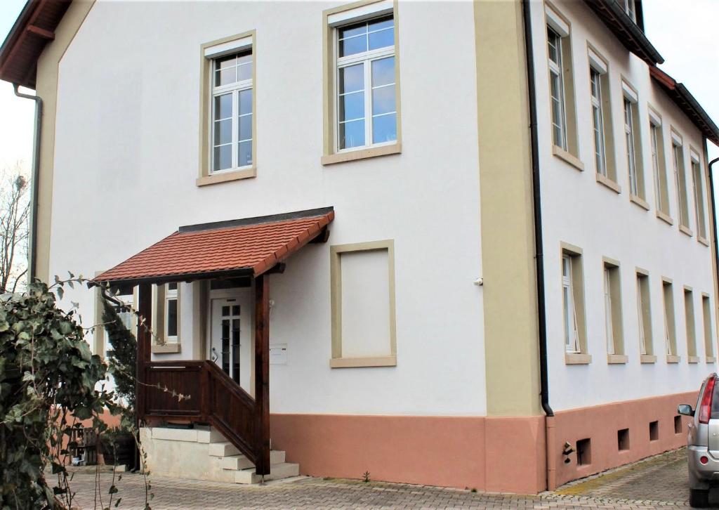 een wit gebouw met een bruine deur en ramen bij Ferienwohnung Renchglück in Renchen