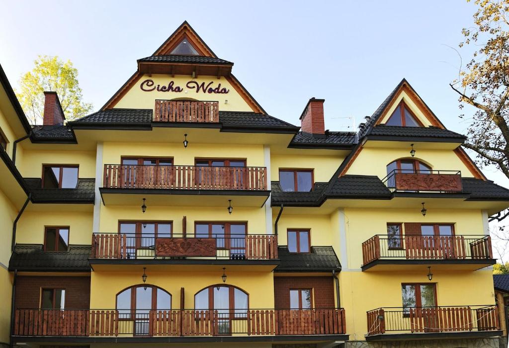 un edificio giallo con tetto a gambero di Apartamenty Cicha Woda a Zakopane