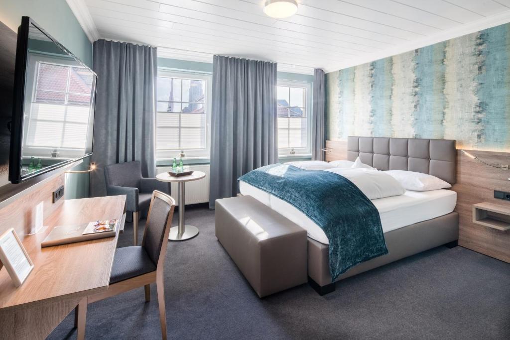 una camera d'albergo con letto, scrivania e sedie di Hotel zur Post NEW STYLE a Garrel