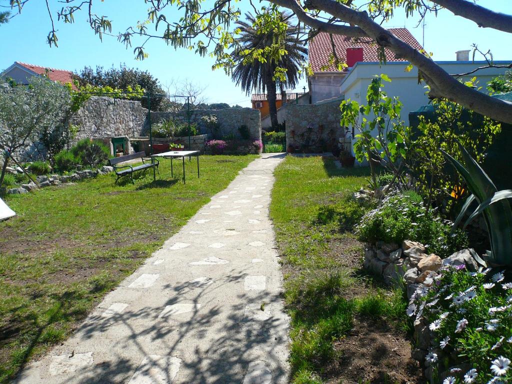 a stone path in a garden with a bench at Guesthouse Palma in Mali Lošinj
