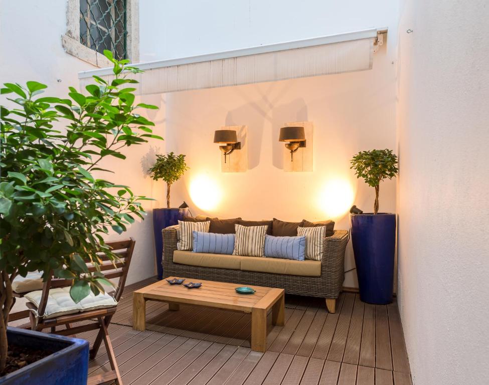 A small, plant-filled seating nook with a sofa, coffee table and outdoor-style flooring.