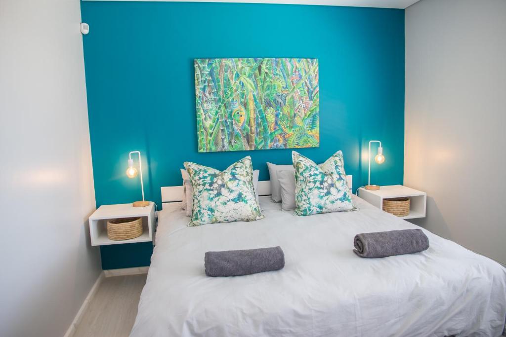 ein blaues Schlafzimmer mit einem großen Bett mit zwei Kissen in der Unterkunft Turmalin Cottage Unit 1 in Swakopmund
