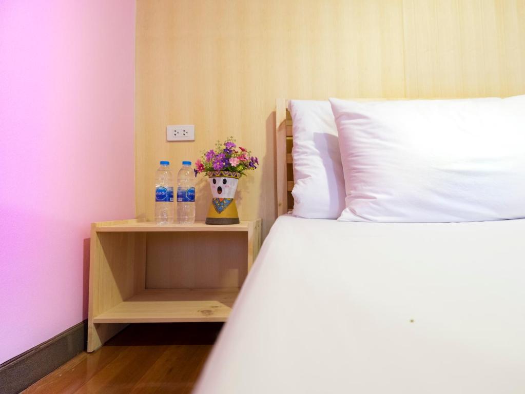 曼谷的住宿－我愛我家旅舍，床头柜上床,床上有两瓶水和鲜花