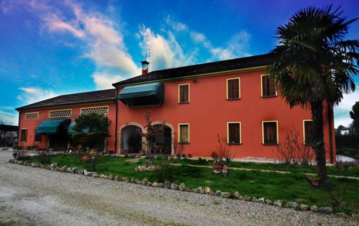 una casa rossa con una palma di fronte di Agriturismo I Marzemini a Legnaro