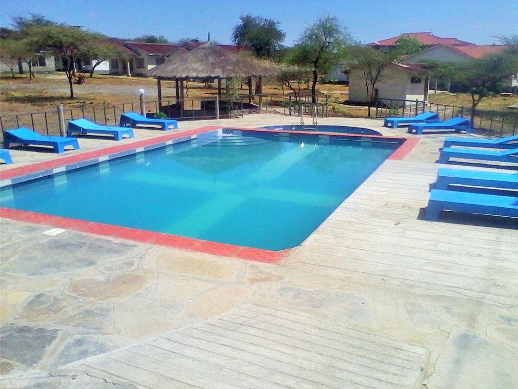 a large swimming pool with blue lounge chairs and sidx sidx sidx at Sandai Resort Lake Baringo in Ol Kokwe