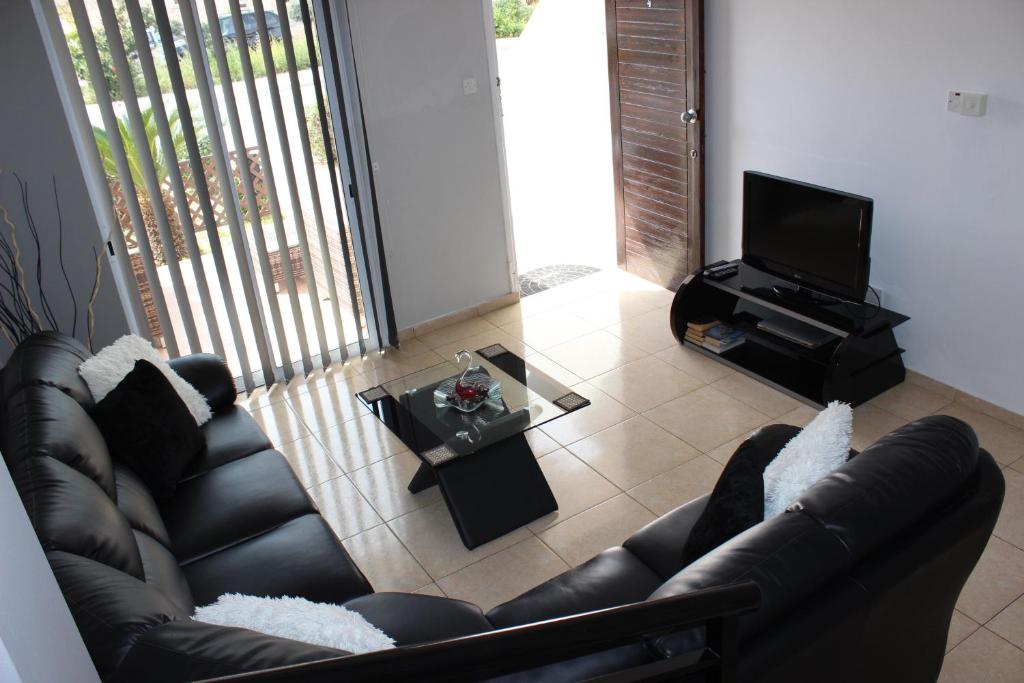 a living room with a leather couch and a television at Diana Townhouse 2 in Paphos