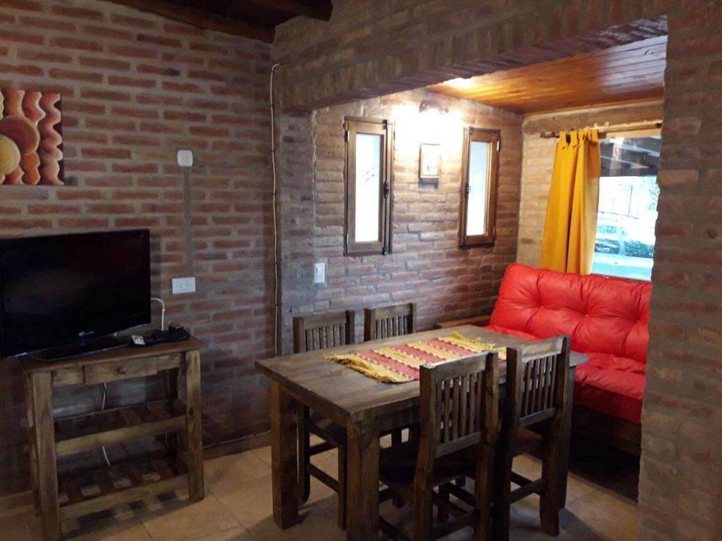 sala de estar con mesa y sofá rojo en Magma Village en Los Reartes