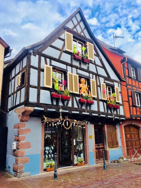 a black and white building with flowers in the windows at Manala - Maison Alsacienne avec Terrasse in Kaysersberg