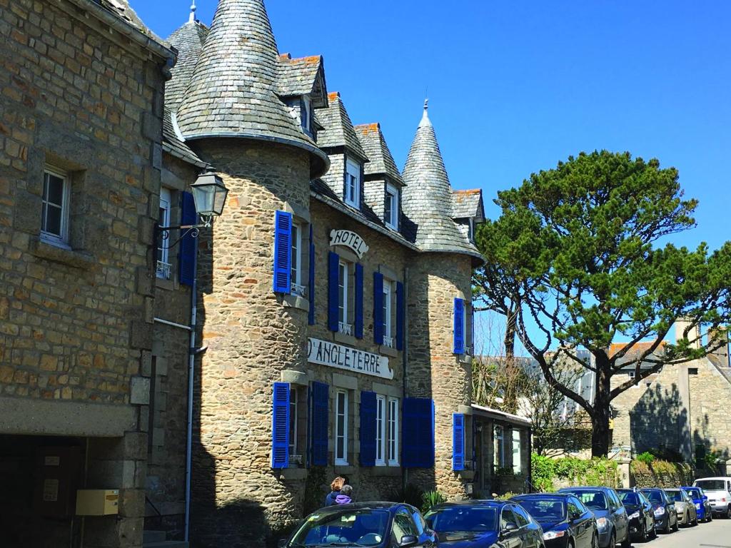 un grand bâtiment en briques avec des fenêtres bleues et des tourelles dans l'établissement Hotel D'Angleterre, à Roscoff