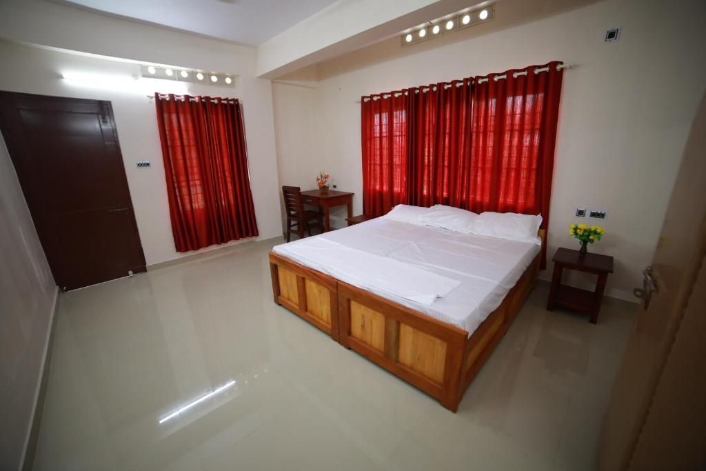 a bedroom with a large bed and red curtains at Indeevaram Residency in Trivandrum