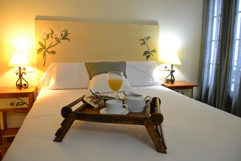 uma bandeja com um copo de sumo de laranja e uma bebida numa cama em Hostal Toribio em Galaroza