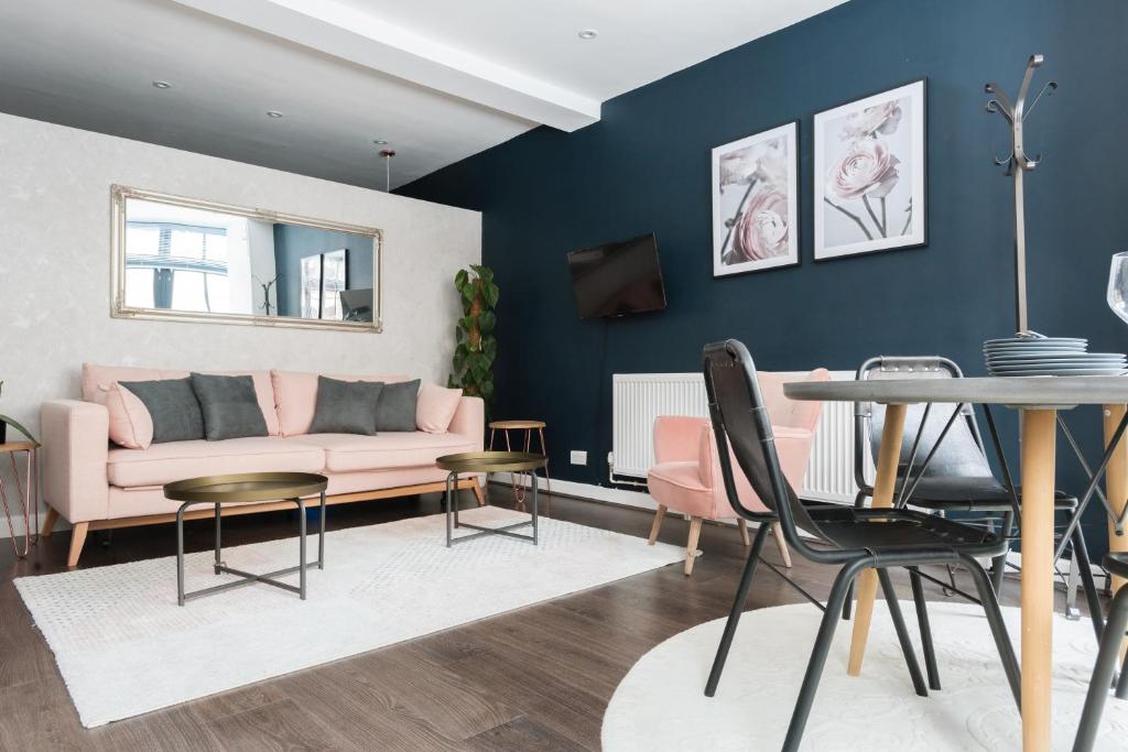 a living room with a pink couch and a table at The Paddington Studio - Cool & Stylish 1BDR Mews in London