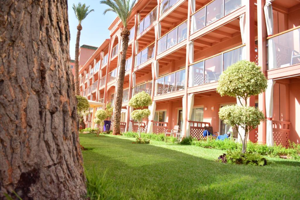 an exterior view of a building with palm trees at Savoy Le Grand Hotel Marrakech in Marrakesh