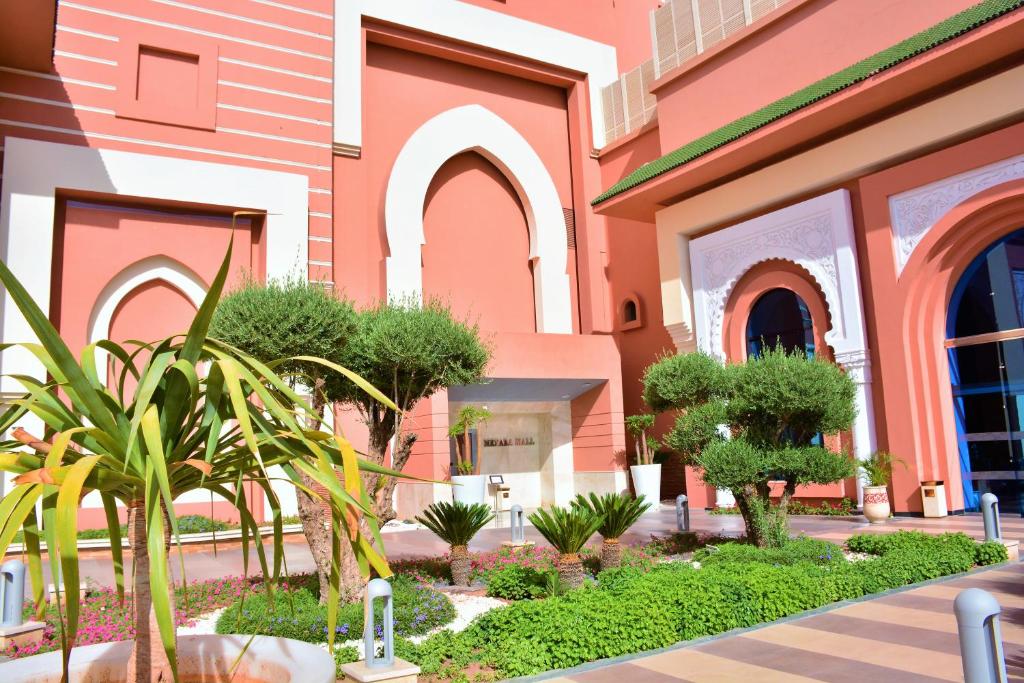 a building with trees and plants in front of it at Savoy Le Grand Hotel Marrakech in Marrakesh