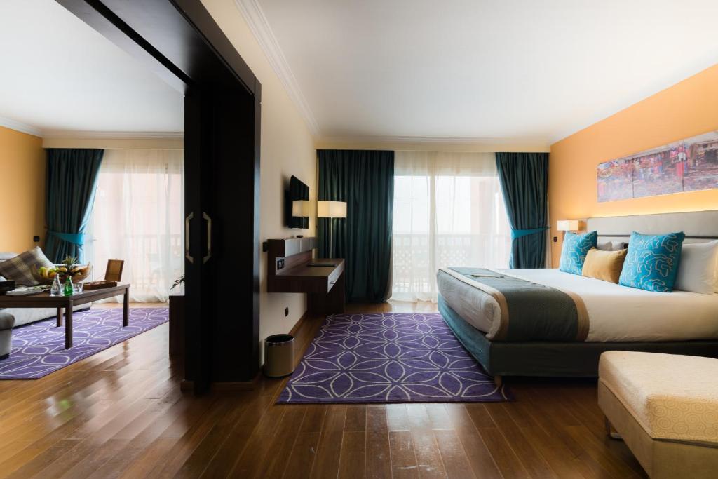 a hotel room with a large bed and a desk at Savoy Le Grand Hotel Marrakech in Marrakesh