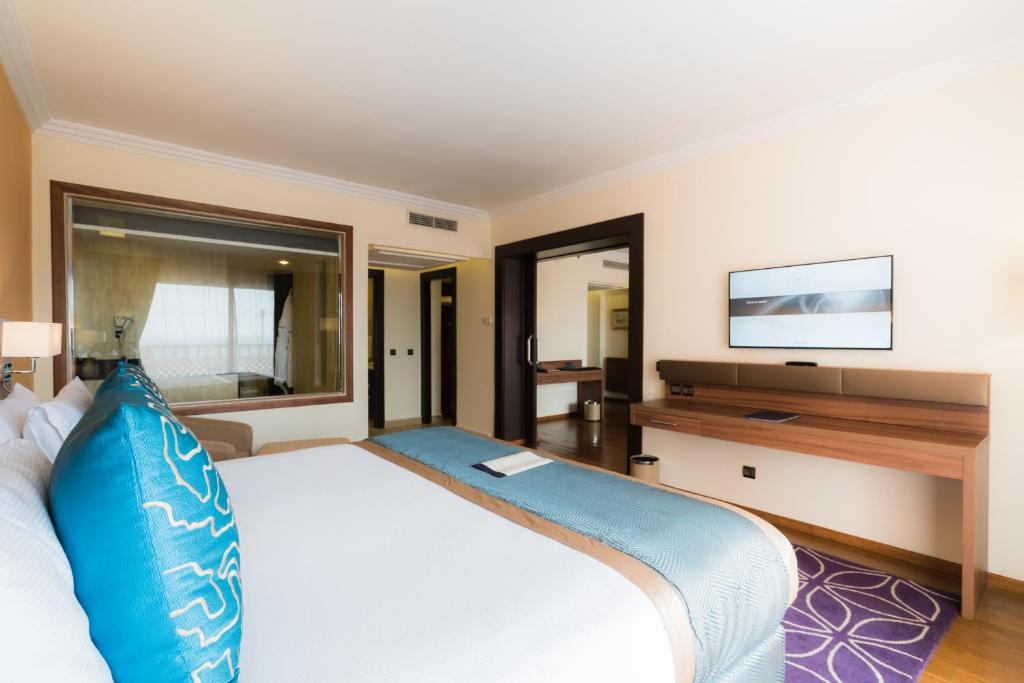 a bedroom with a large bed and a flat screen tv at Savoy Le Grand Hotel Marrakech in Marrakesh
