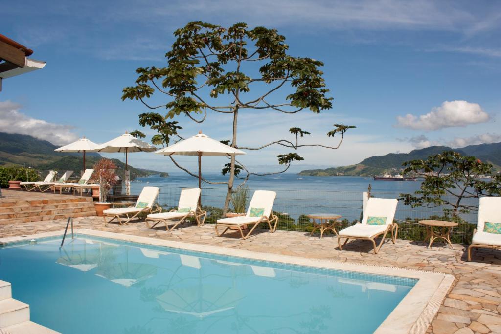a swimming pool with chairs and a view of the water at Hotel Vista Bella in Ilhabela