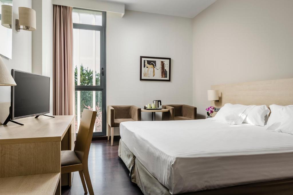 a hotel room with a bed and a desk and a television at Hotel Exe Barcelona Gate in Sant Joan Despí