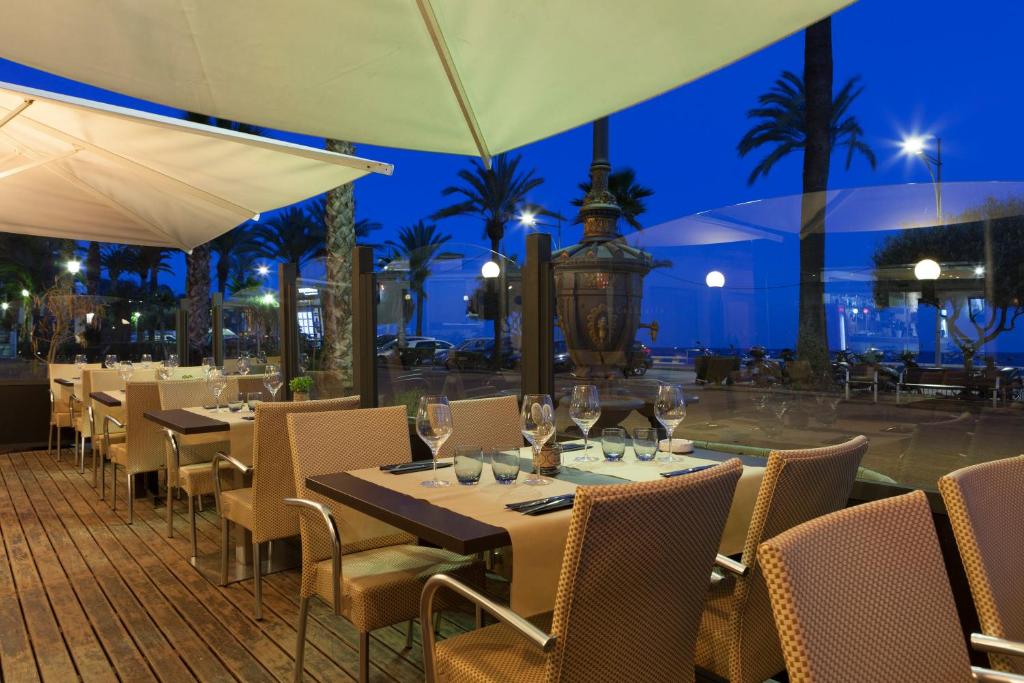 a restaurant with tables and chairs and a pool at night at URH Excelsior in Lloret de Mar